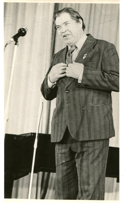 Фотография: У микрофона Касаткин П.Е., фотопортрет поколенный, 3/4, руки на груди. Стоит у рояля перед микрофоном.