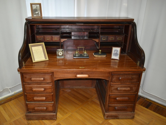 Стол письменный на двух тумбах. В левой тумбе - 4 ящика, в правой - 3 ящика (один ящик сдвоенный, глубокий). Между тумбами один большой ящик. Бюро стола разборное, состоит из серии ящичков каталожного типа и полочек различных размеров. Ручки у ящичков медные. Сверху, по обеим сторонам стола, установлены боковины. Стол клеенный из различных сортов ценных пород дерева. Его поверхность отполирована, коричневого цвета. Стол местами поврежден.