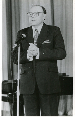 Фотопортрет Гончарова Ю.Д., поколенный, почти анфас, руки на груди, пальцы соединены в замок, в очках.