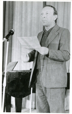 Фотопортрет Луткова Г., поколенный, 3/4, в руках лист бумаги. Стоит перед микрофоном  у рояля.