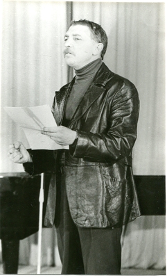 Фотопортрет Шевченко О.Ф., поколенный, 3/4, в руках листы бумаги. Стоит перед микрофоном  у рояля.