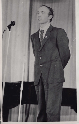 Фотопортрет Будакова В., поколенный, 3/4. Стоит перед микрофоном  у рояля.