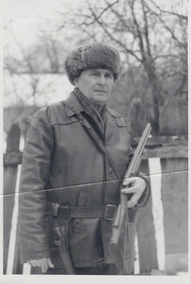 Фотография черно-белая: Кравченко Я.Ф., поколенный, в правой руке ружье, на поясе нож. Одет в кожаную куртку, зимнюю шапку. Острогожск, 1980 г.